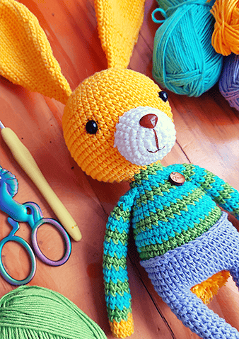 Amigurumi de un conejo amarillo con una camisa a rayas