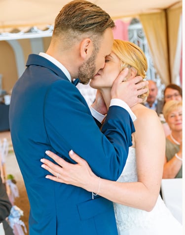 Braut und Bräutigam küssen sich während der Trauung und halten sich dabei liebevoll im Arm.