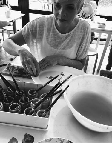 the artist creating with paints and paint brushes and big bowl of water