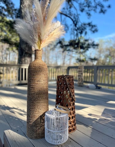 Floral pampas grass in textured floor vase with decorative lanterns luxury picnic setup  