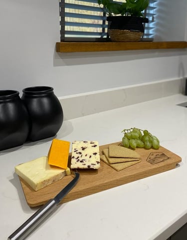 a cheese board with cheese and grapes on a kitchen bench