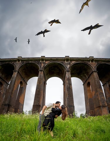 Romantic couple under bridge with birds in sky – cinematic outdoor photography by Fred Art Studio