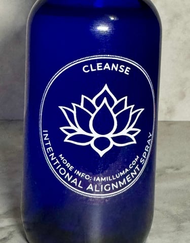 a vibrant blue glass spray bottle with a white lotus label on the front that says Cleanse