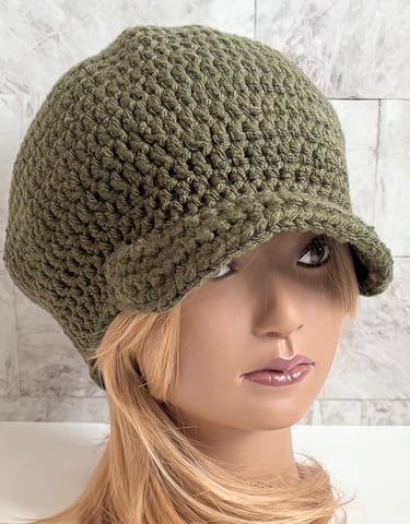 Woman wearing an olive green brimmed crochet Newsboy cap.