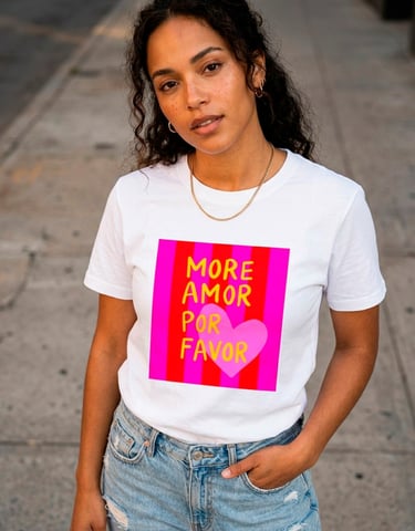 Woman wearing a white More Amor Por Favor graphic t-shirt with a pink heart and red stripes.