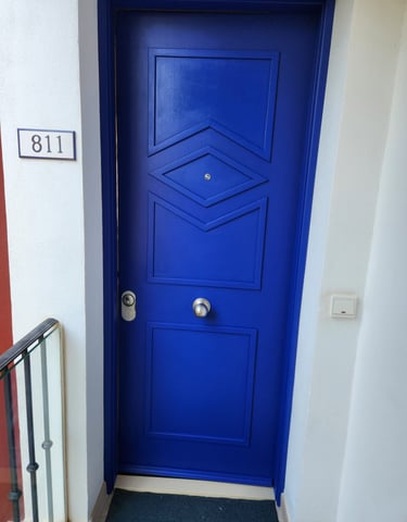 Modern vibrant blue entry door with geometric wood panels and house number 811 on white wall.