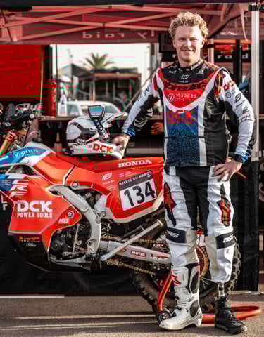 Professional rally racer with a prosthetic leg standing next to his Honda dirt bike at Rallye du Maroc.