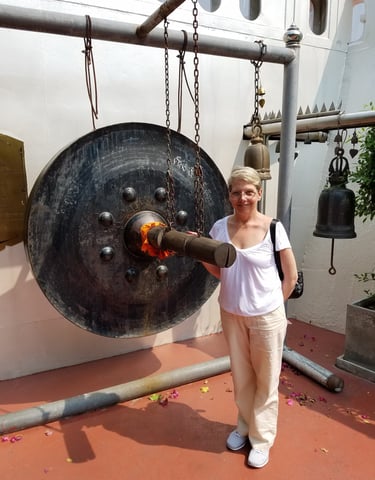 Ladi Michelle bangs the gong at Wat Saket Temple in Bangkok