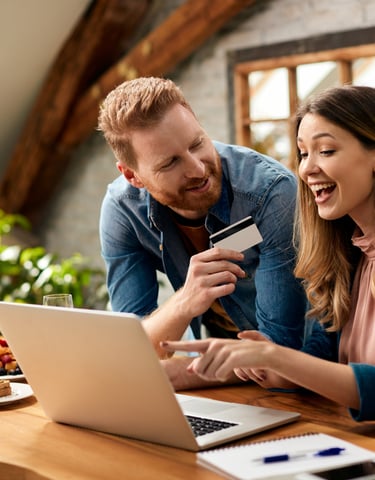 a man and woman are looking at a laptop and credit card