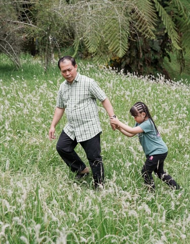 Iqbal family walking together in an open grass field at Kebun Raya Bedugul Bali.