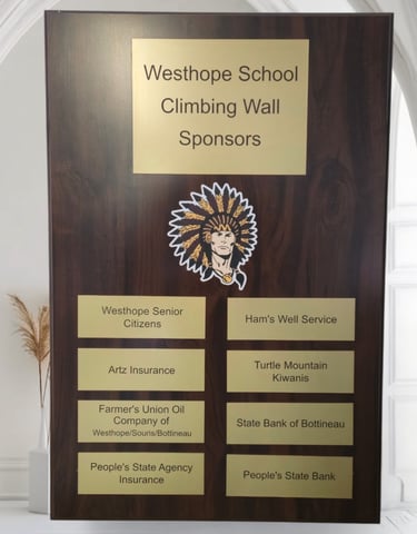A sponsor plaque hanging on a wall showing school and sponsor names
