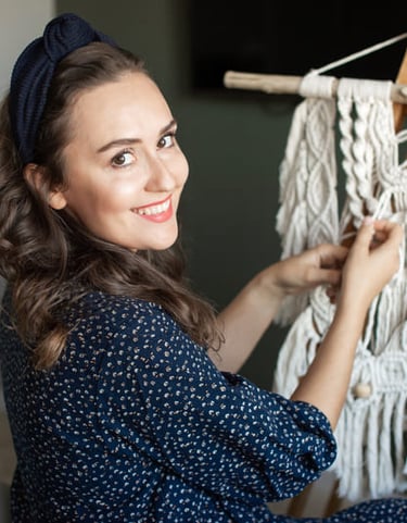 mujer sonriente tejiendo macramé