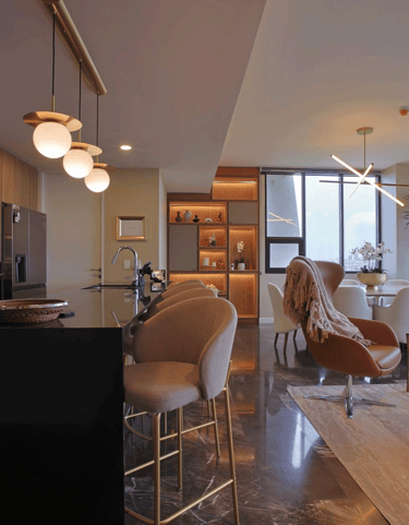Sala comedor moderno con acabados en mármol, iluminación cálida y mobiliario contemporáneo | KARÄNA