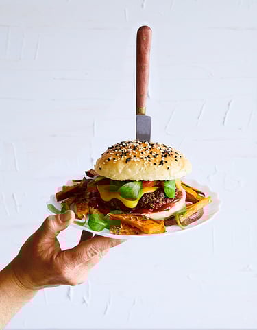 a person holding a plate with a hamburger burger on it