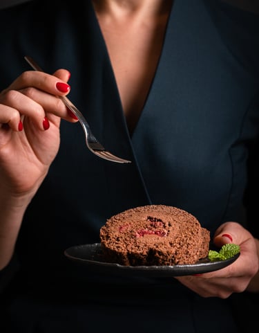 a woman in a black dress holding a fork and a desert