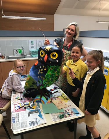 Laura Fearn painting an owl sculpture with pupils from a local school