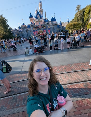 Katie Matzenbacher, standing in front of Sleeping Beauty's castle at Disneyland in California