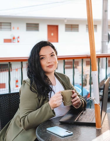 Raabe sentada com notebook segurando xícara..