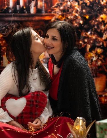 a girl kissing her mother under the Christmas tree