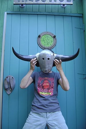 Talbotics t-shirt wearer holding a mask by the studio door.