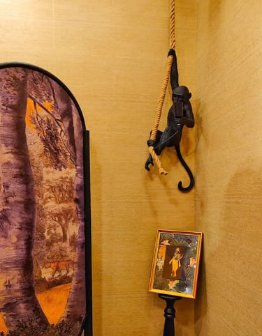Black monkey hanging lamp with rope in a room featuring jungle themed wall art and decor.
