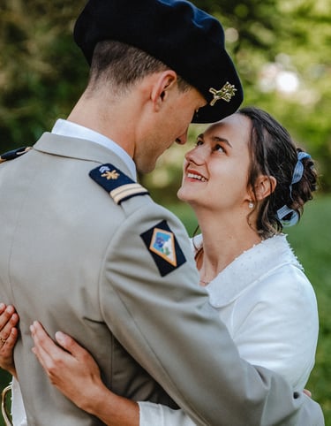 Une mariée souriante enlace son époux, vêtu d'un uniforme militaire à Bois-d'Oingt