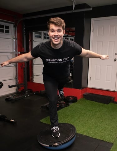 dustin king on a bozu ball smiling and doing a plane pose