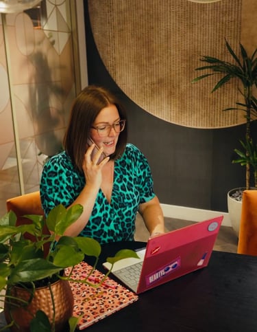 Gabi on the phone sitting at her desk, inviting you to work with her one to one
