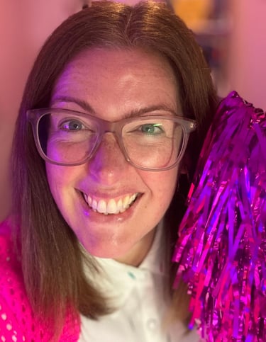 Gabi holding a pink pom pom, to welcome you to sign up to her newsletter, the leopard pages. 