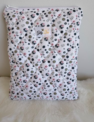 Quilted floral book sleeve with a zipper, featuring pink and green flowers on white fabric.