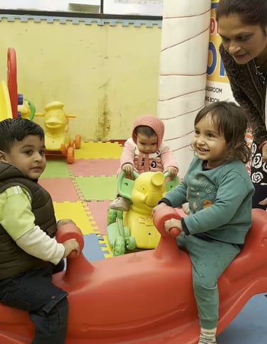 Young children playing on colorful indoor playground equipment with a teacher supervising at a daycare center.