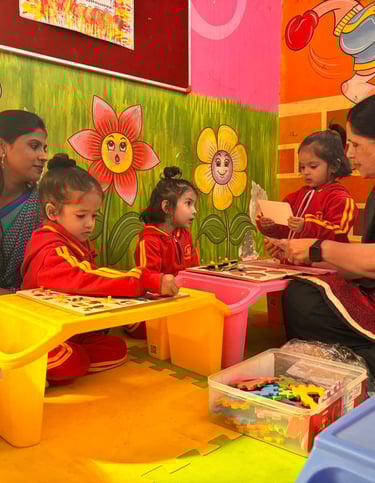 Preschool students in red uniforms solve educational puzzles with teachers in a colorful play school classroom.