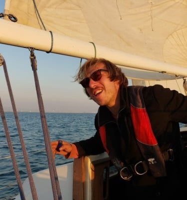 a man in a black jacket and sunglasses on a boat