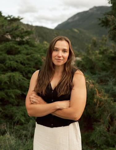 a woman in a white dress standing in front of a mountain