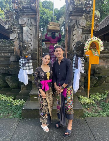 Couple balinais en tenue traditionnelle devant un temple lors des célébrations.