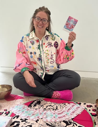 Gabi sitting on the floor holding an oracle card to welcome you to the leopard coven