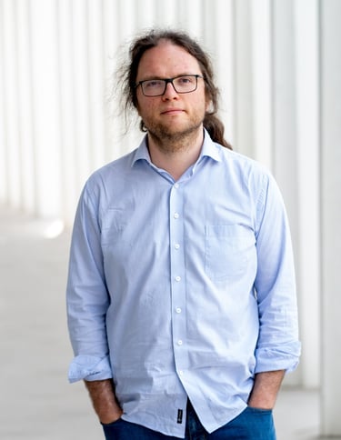a man with long hair and glasses on a sidewalk