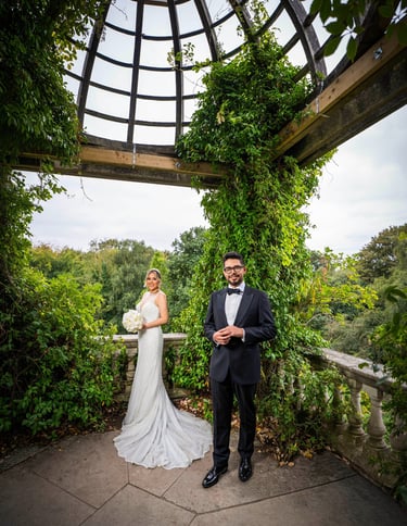 Bride and groom posing under a vine-covered pavilion, captured by Fred Art Studio