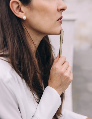 Profile of a woman touching her chin with a pen.