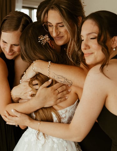Quatre demoiselles d'honneur émotives qui enlacent une mariée