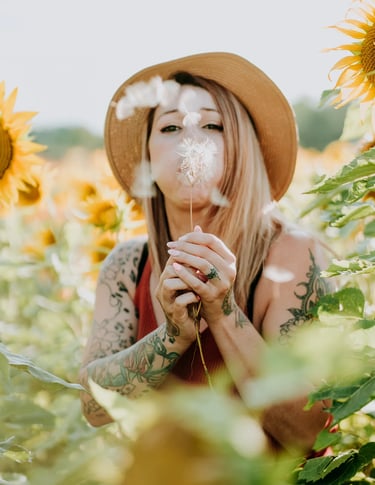 une femme souffle sur un pissenlit