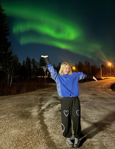 a woman standing under the northern lights