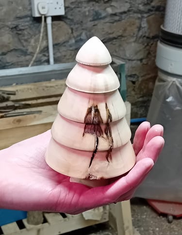 A turned wooden fir tree standing on a hand