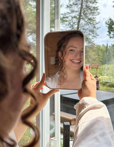 une mariée se regarde dans le miroir après son maquillage et sa coiffure et elle est heureuse