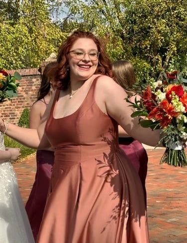 a bridesmaid in a rose gold dress holding a bouquet of flowers