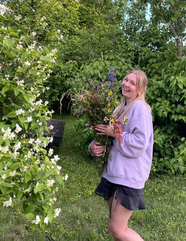 moteris apsirengusi violetiniu megztuku laiko gėles ir juokiasi