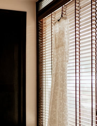 a wedding dress hanging in a window with a dress hanging from a window