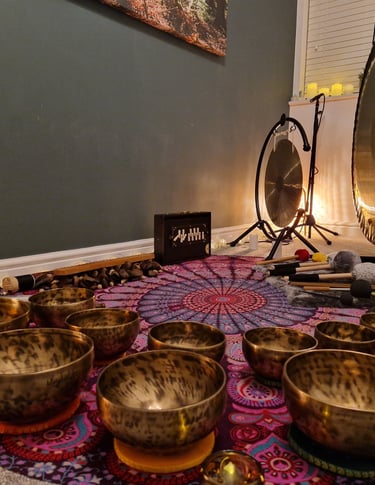 Shruti box, chimes, gongs, and many singing bowls arranged on a mat