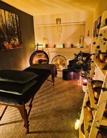 Studio with treatment couch, chair, gongs and shelf with Himalayan singing bowls
