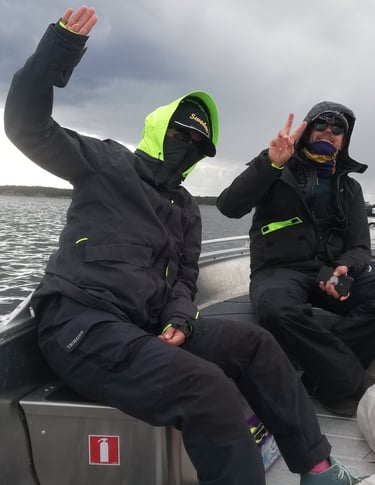 two people in black jackets and green pants sitting on a boat